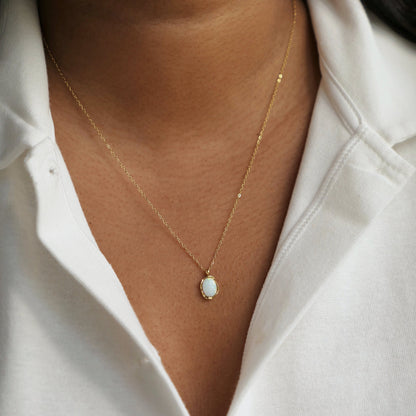 Women with white shirt wearing a dainty opal pendant necklace