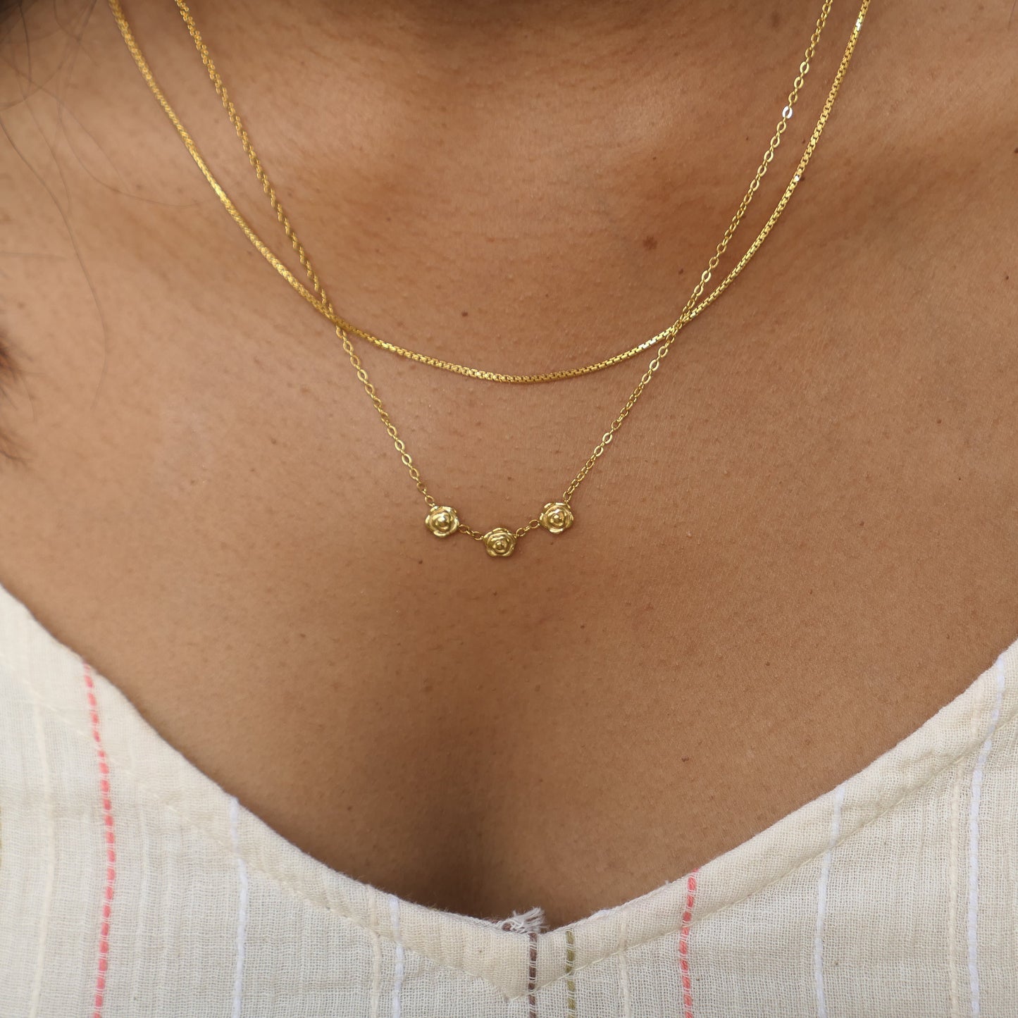 Women in white shirt wearing a dainty rose necklace