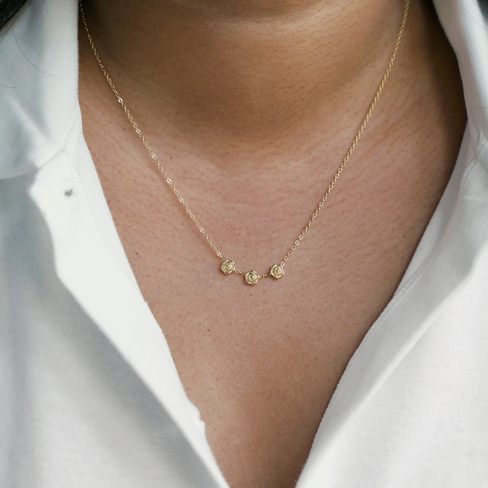 Women in white shirt wearing a dainty rose necklace