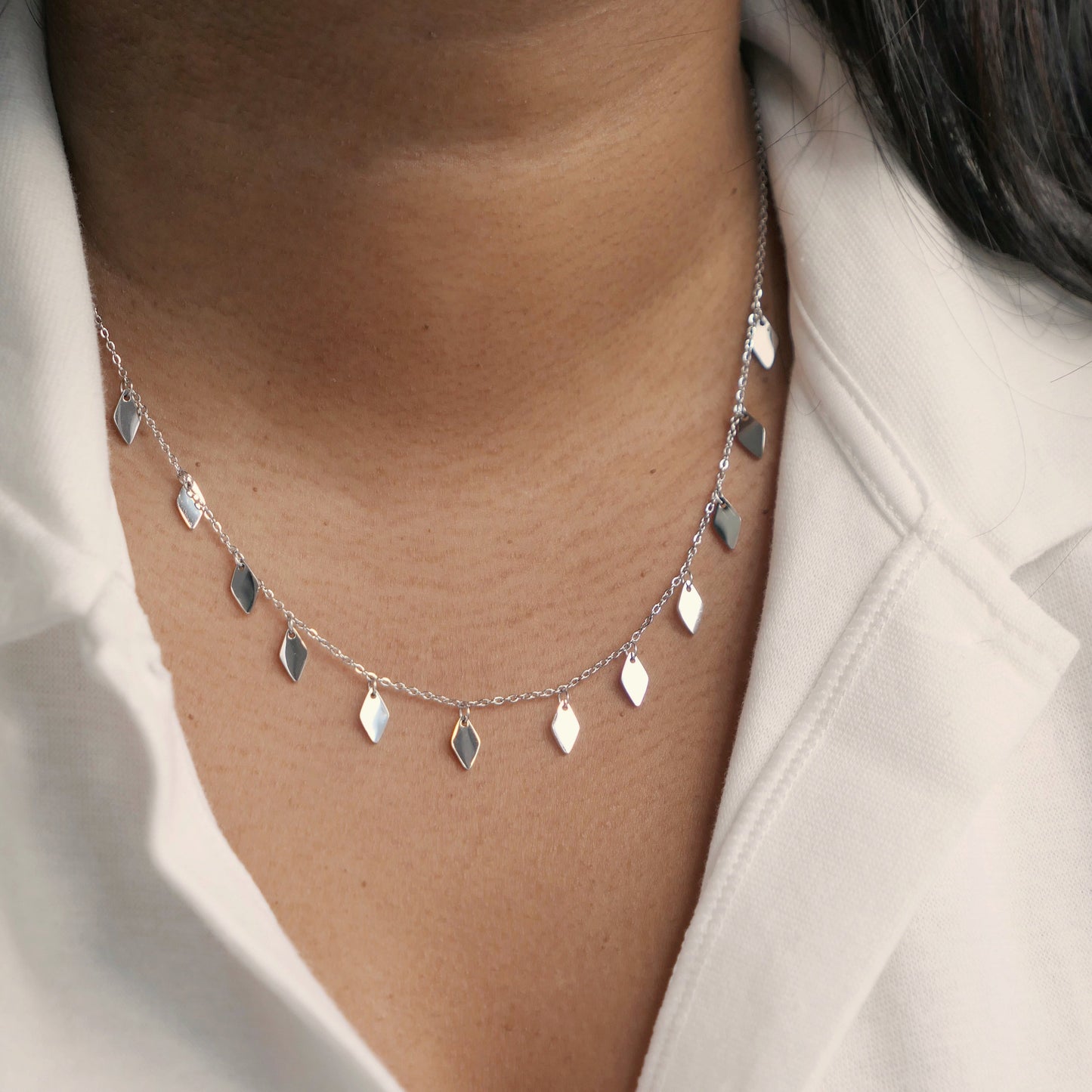 Women in white shirt wearing a shiny tassel necklace in silver