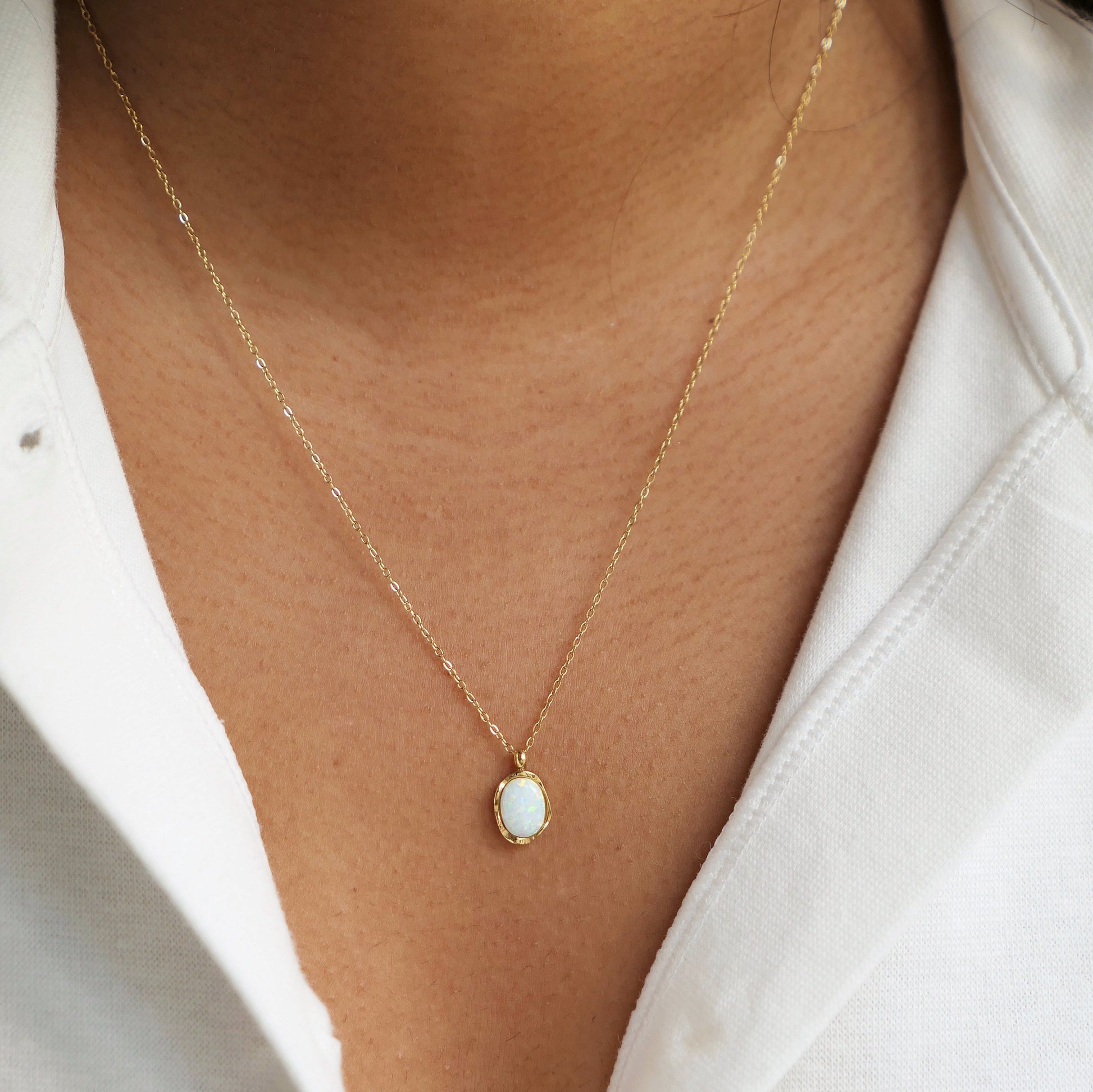 Women with white shirt wearing a dainty opal pendant necklace